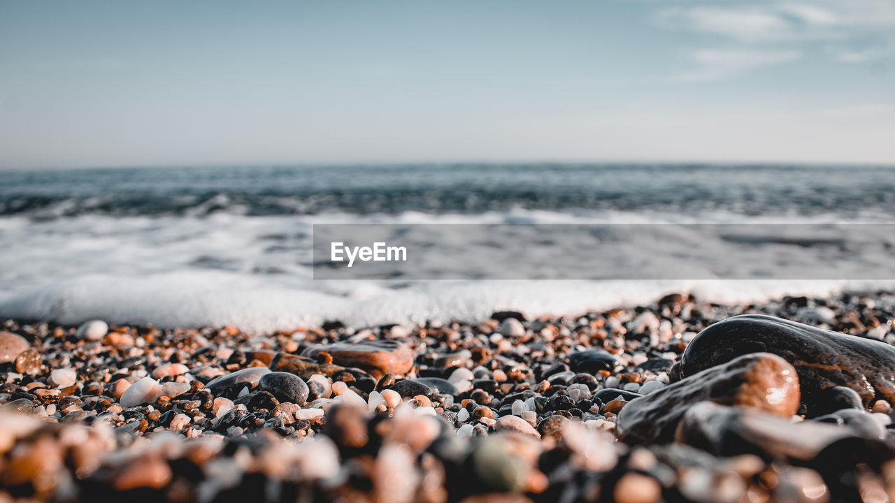 Surface level of pebbles on beach against sky