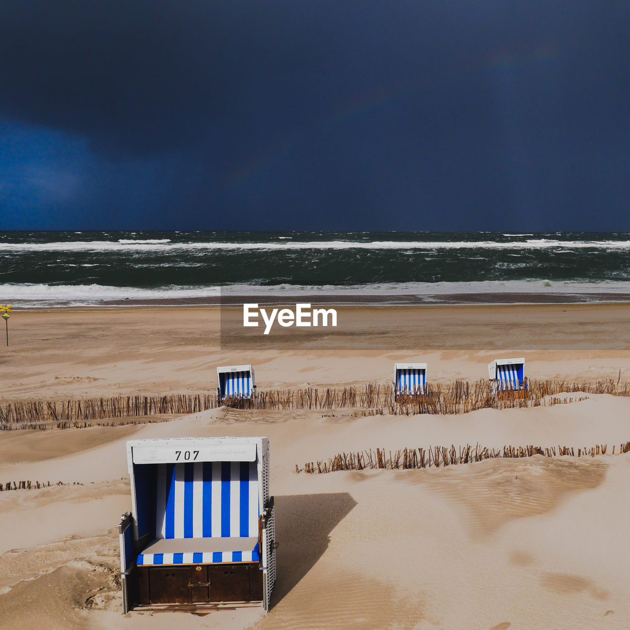 Hooded beach chairs on shore against sky