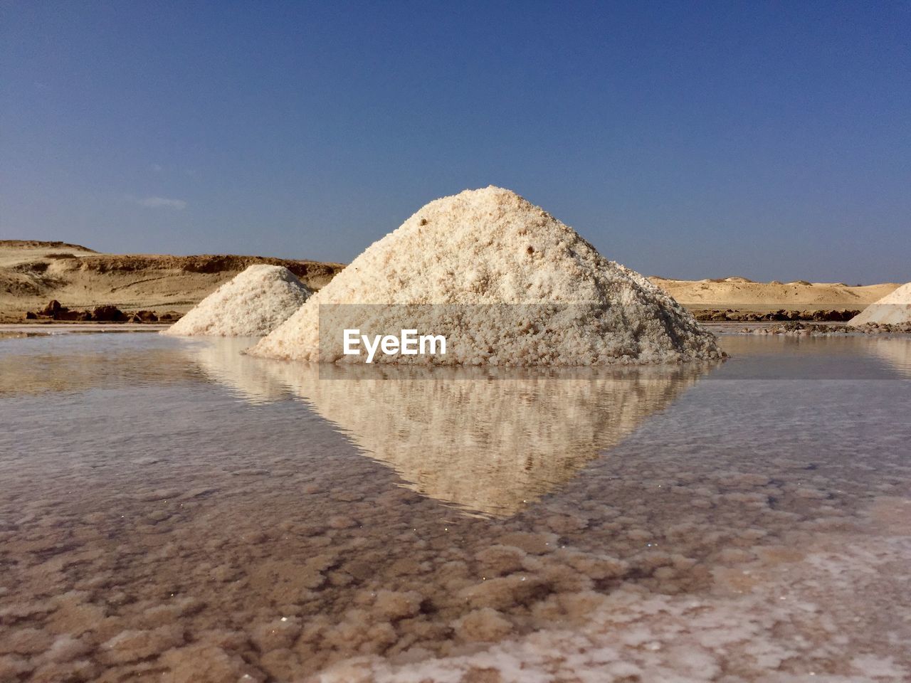 Salt formations in sea against clear blue sky