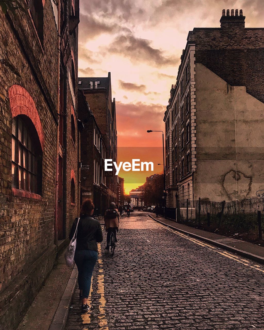 REAR VIEW OF PEOPLE WALKING ON STREET AGAINST SKY