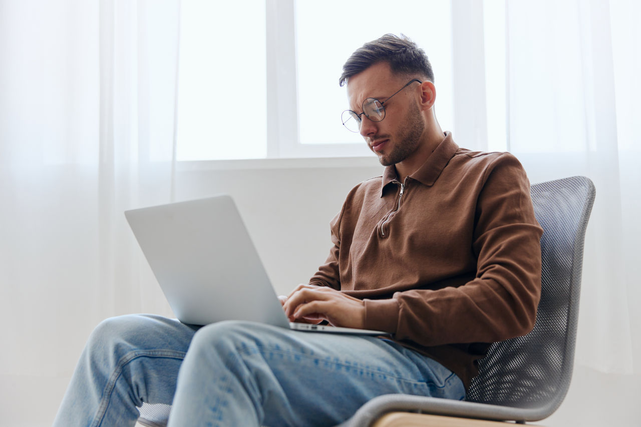 young woman using laptop while sitting on sofa at home