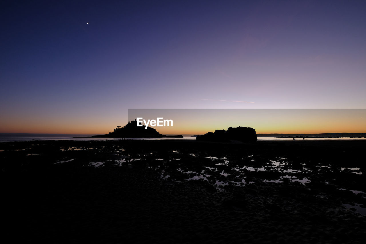 Scenic view of sea against dramatic sky during sunset