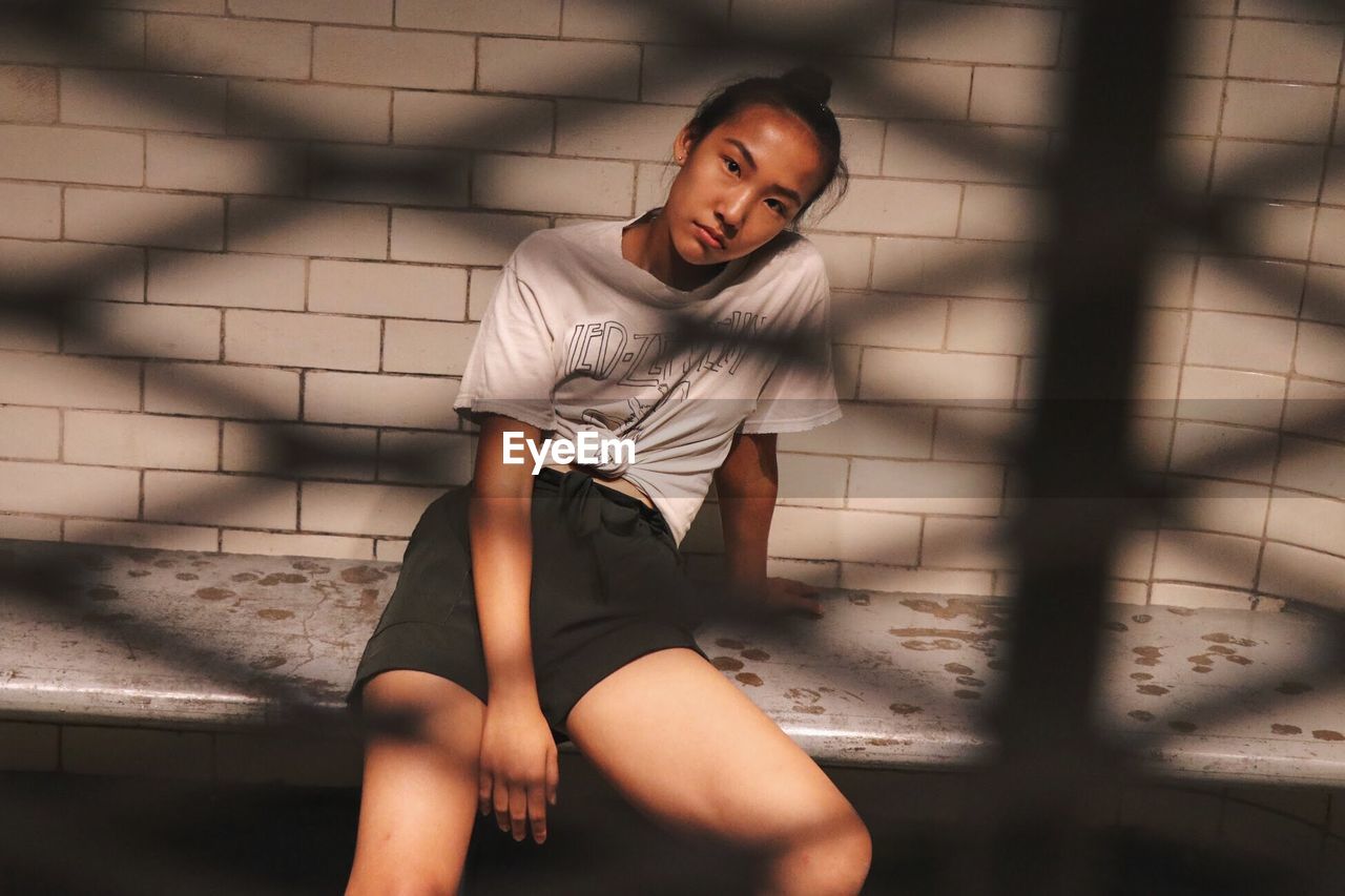 BEAUTIFUL YOUNG WOMAN SITTING ON WALL