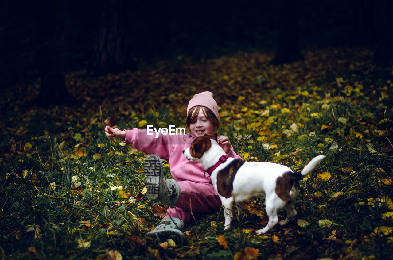 Girl plays with her dog in the autumn forest.