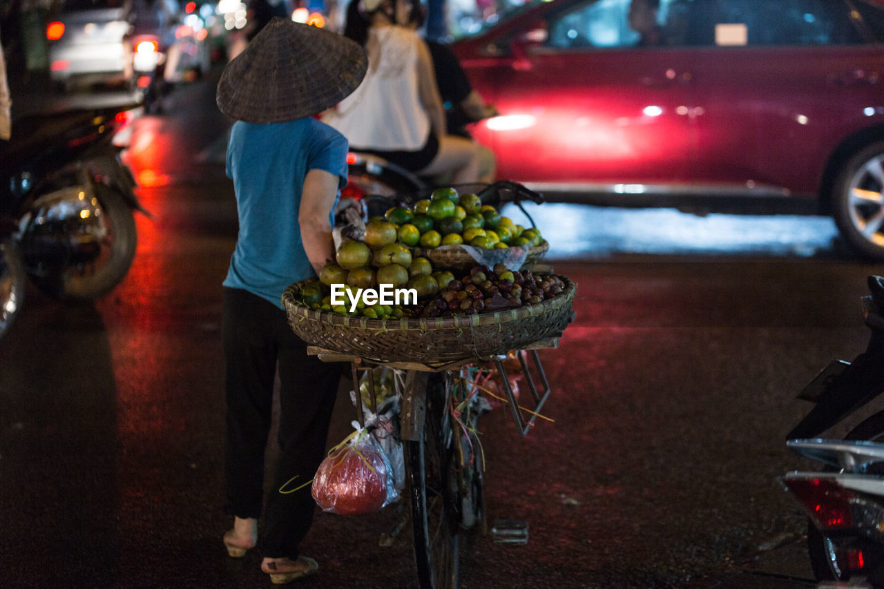 Rear view of person selling fruits on bicycle