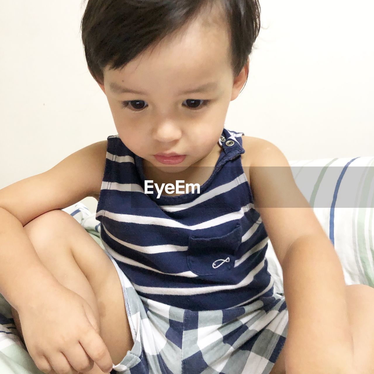 Close-up of cute boy sitting on bed at home