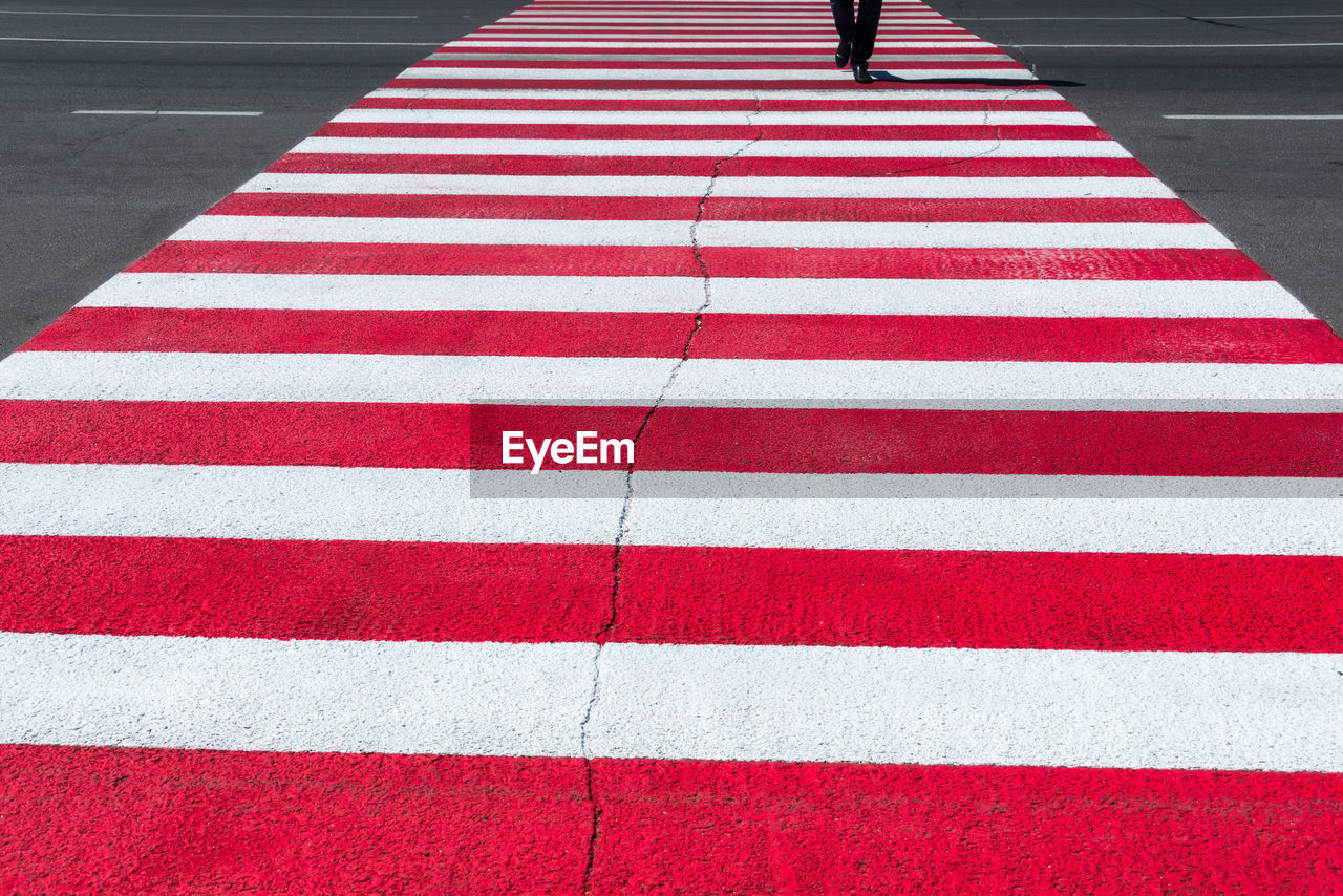 Low section of person walking on zebra crossing