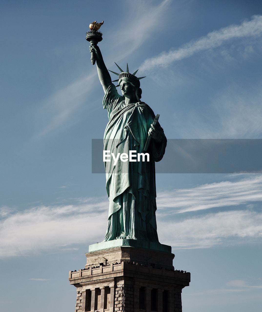 Low angle view of lady liberty against cloudy sky