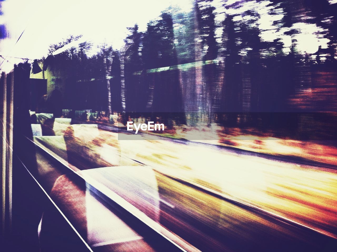 Blurred motion of trees and railroad tracks seen through train window