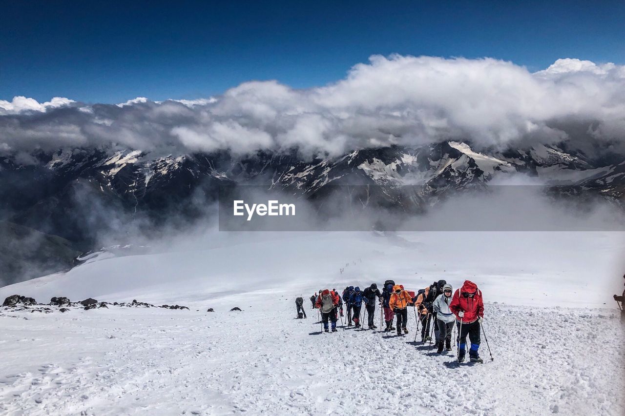 People on snowcapped mountains against sky during winter