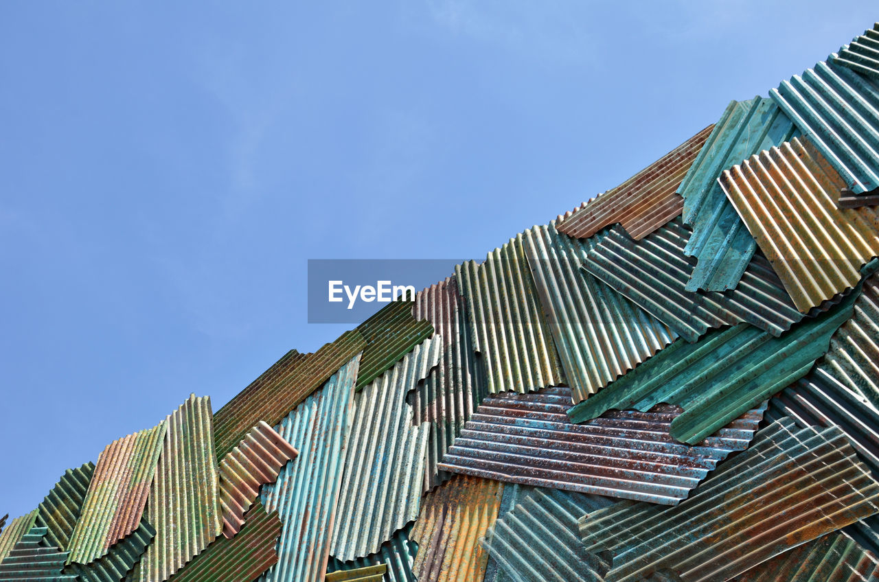 Low angle view of roofs stack against blue sky