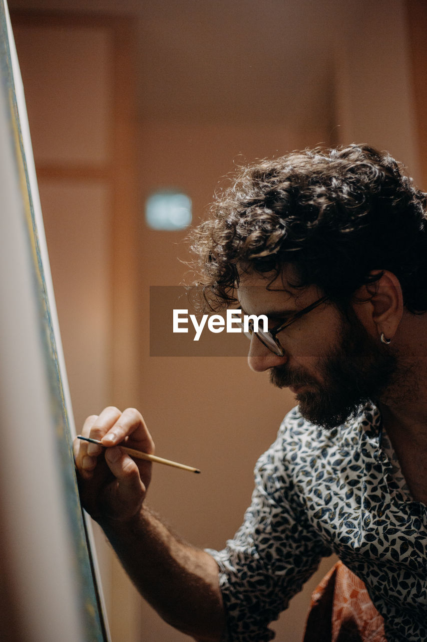 Close-up of man painting on canvas at home