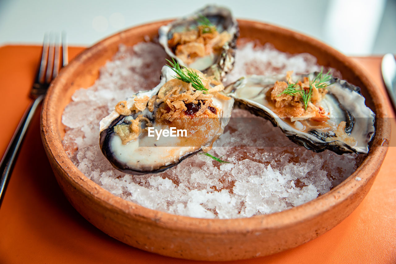 Fresh oysters in shell topping with fried shallot, chili paste, dill and thai style seafood sauce