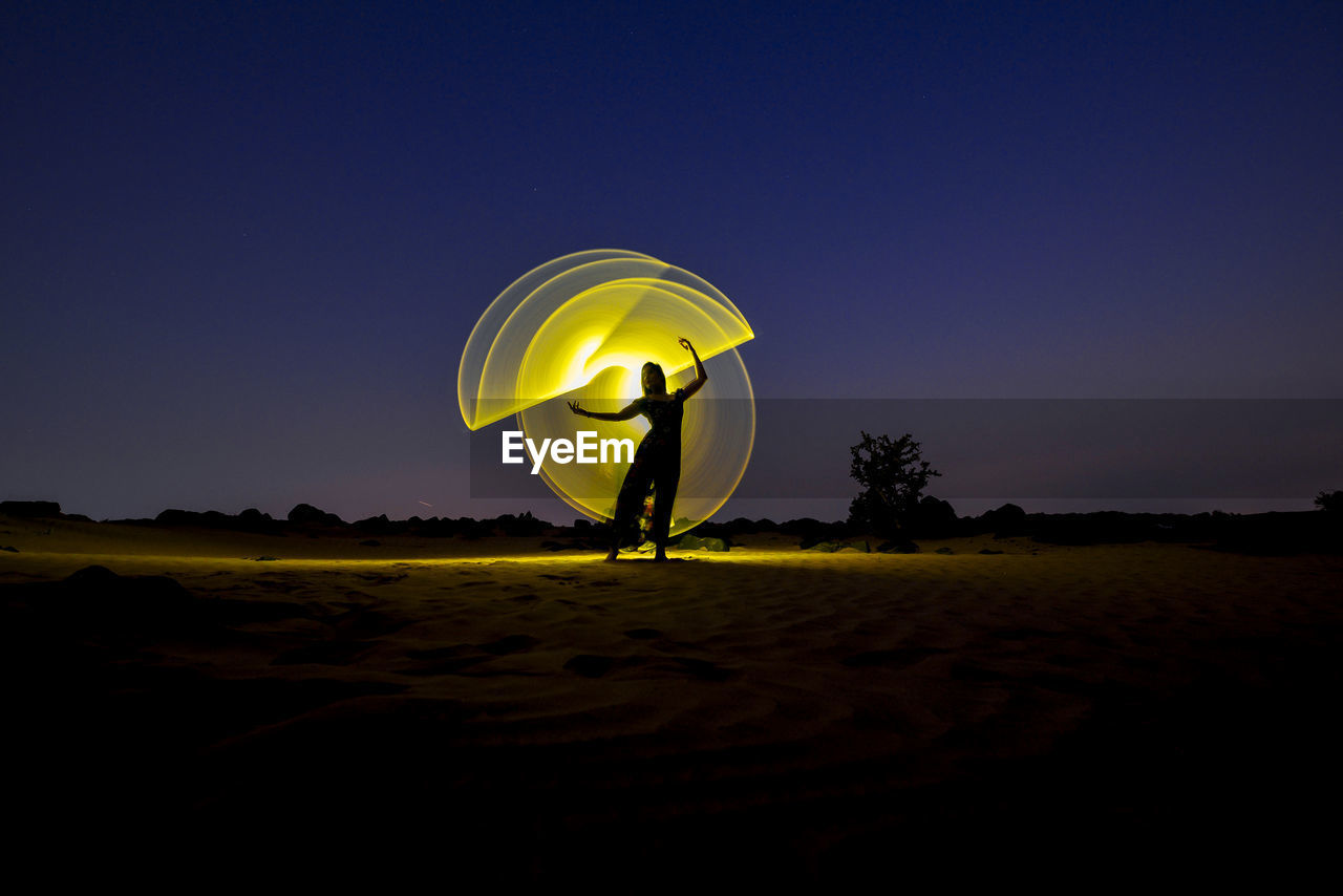 PERSON STANDING ON FIELD AGAINST YELLOW SKY