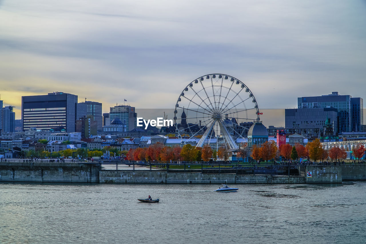 Ferris wheel by river against sky