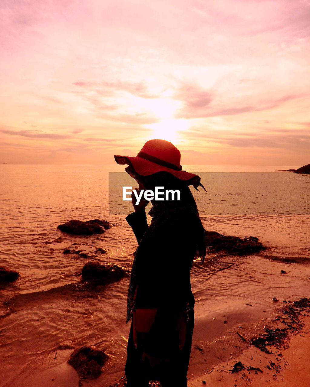 Silhouette woman on beach against sky during sunset