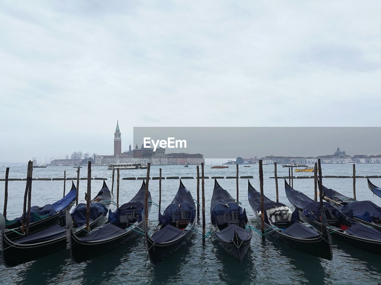 Gondolas moored on grand canal against clear blue sky