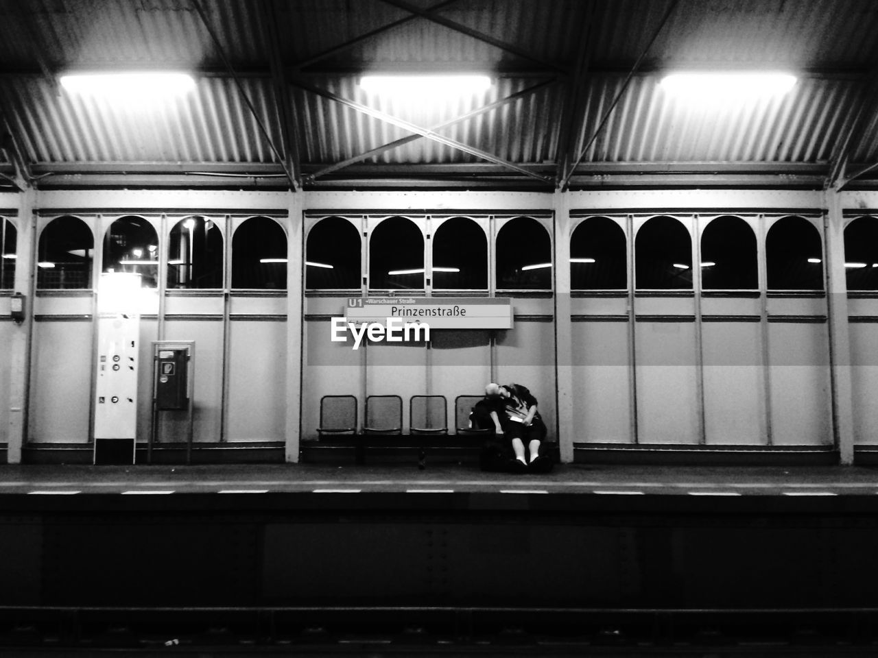 Person sleeping on chairs at railroad station platform