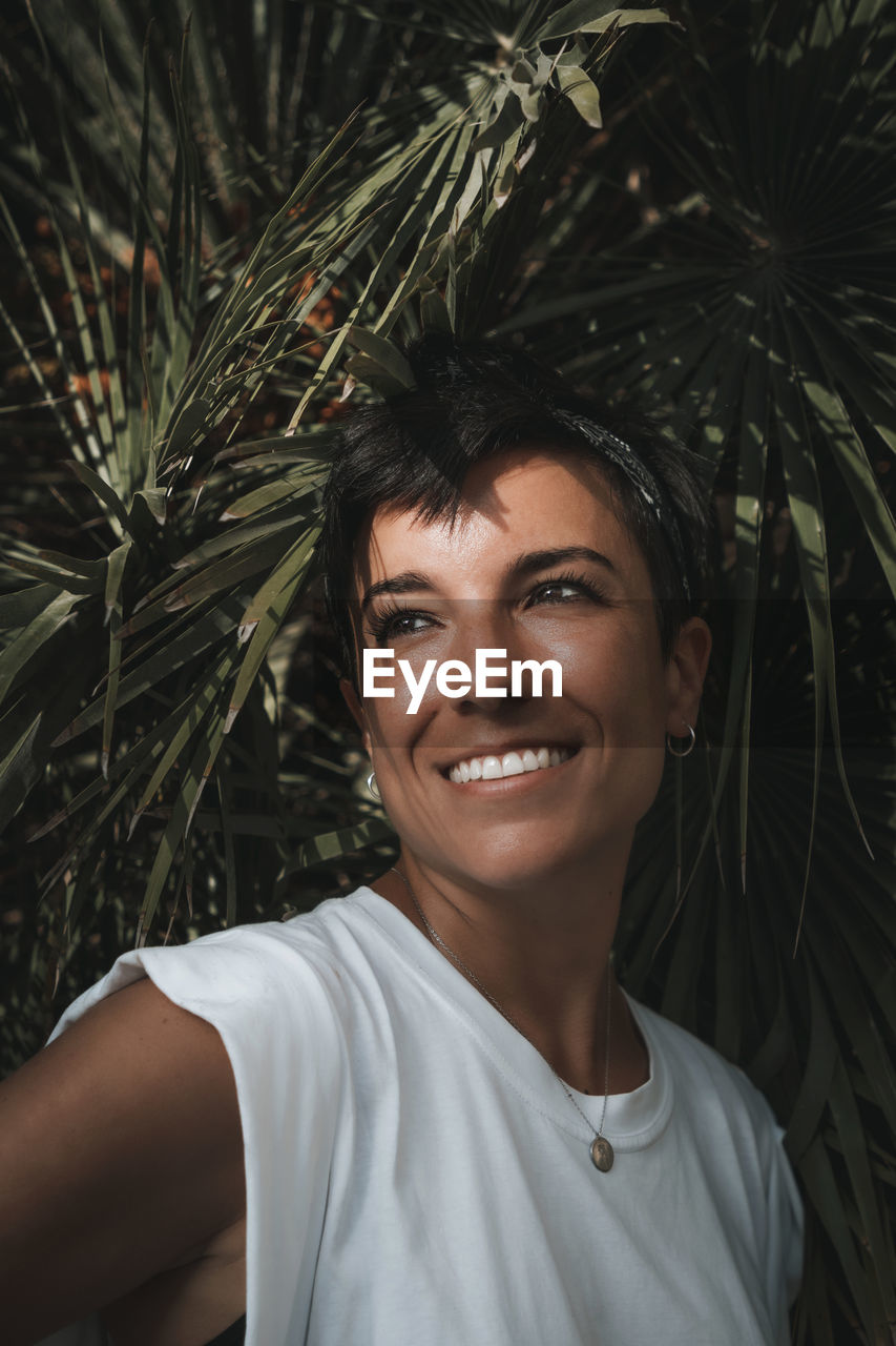 Portrait of beautiful woman smiling with tropical plants in the background 