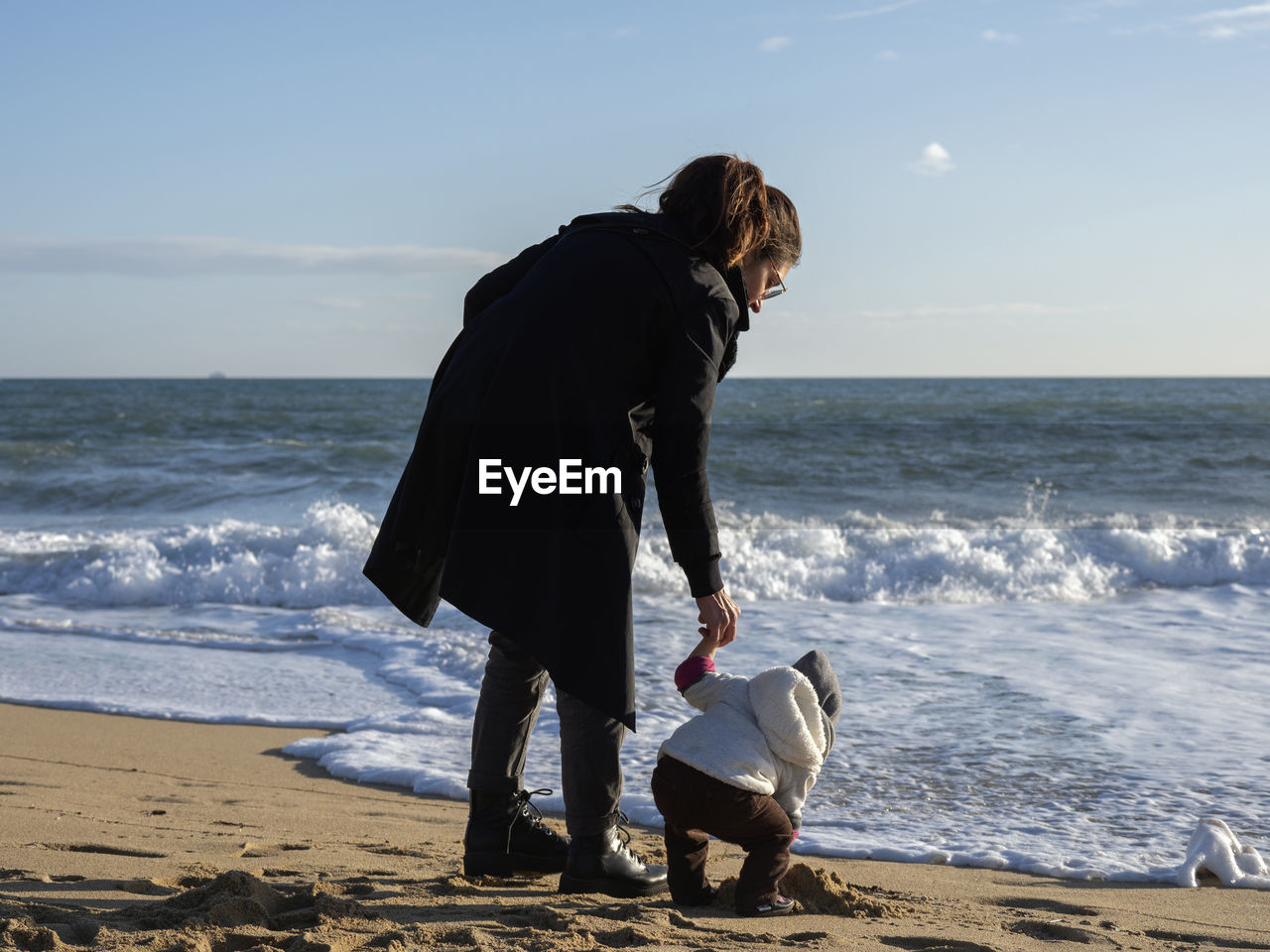 Full length of mother and daughter on beach against sky