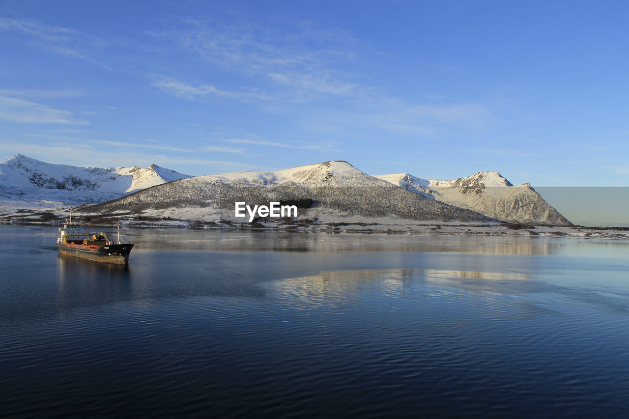 Scenic view of lake and mountains against blue sky