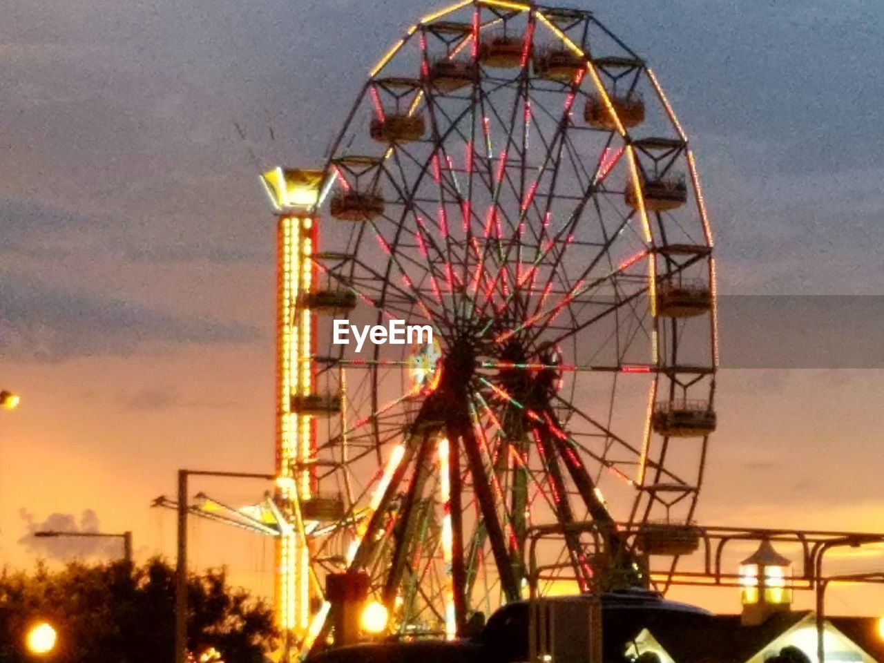 LOW ANGLE VIEW OF ILLUMINATED FERRIS WHEEL AGAINST SKY