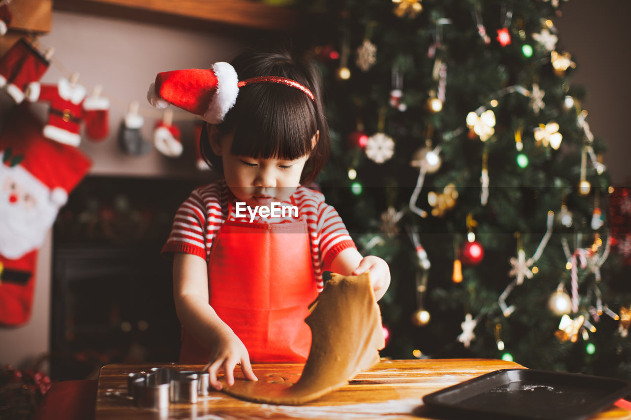 Girl making cookies at table during christmas