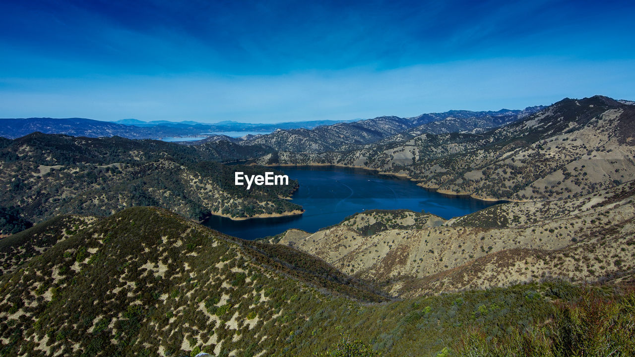 Scenic view of lake and mountains against blue sky