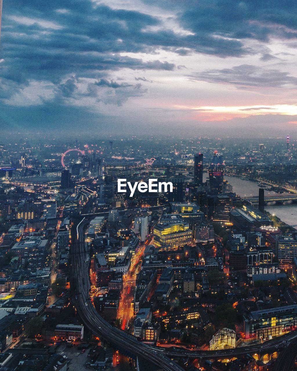 Aerial view of illuminated buildings in city against sky at dusk