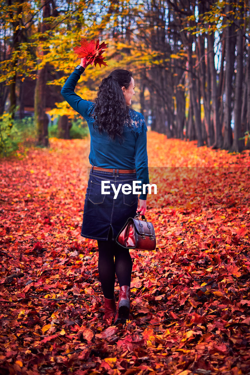 Full length of woman with autumn leaves