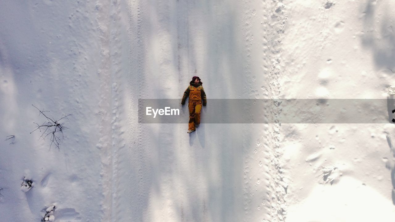 Aerial view of woman lying down on snow covered field