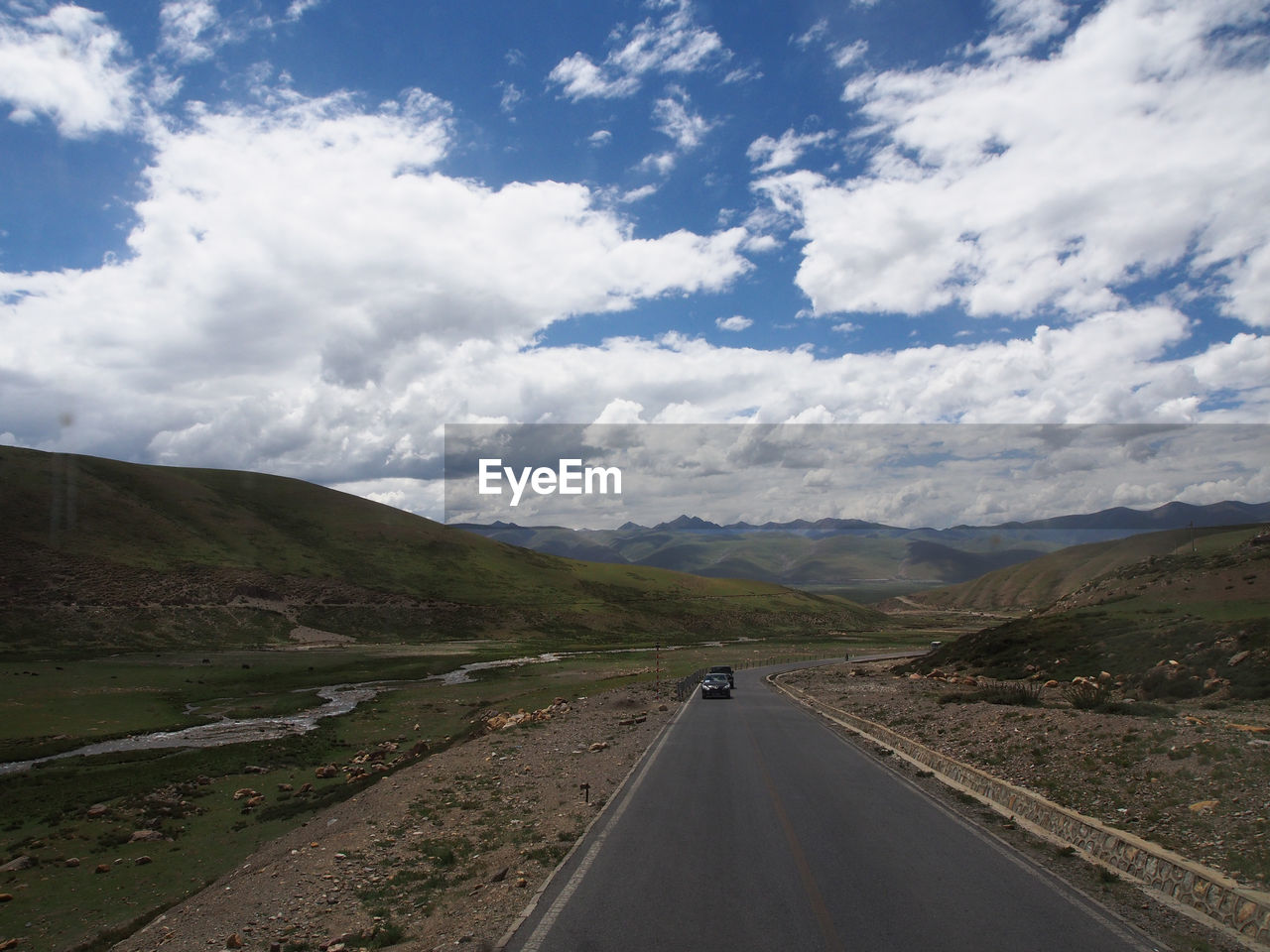 Country road leading towards mountains against sky