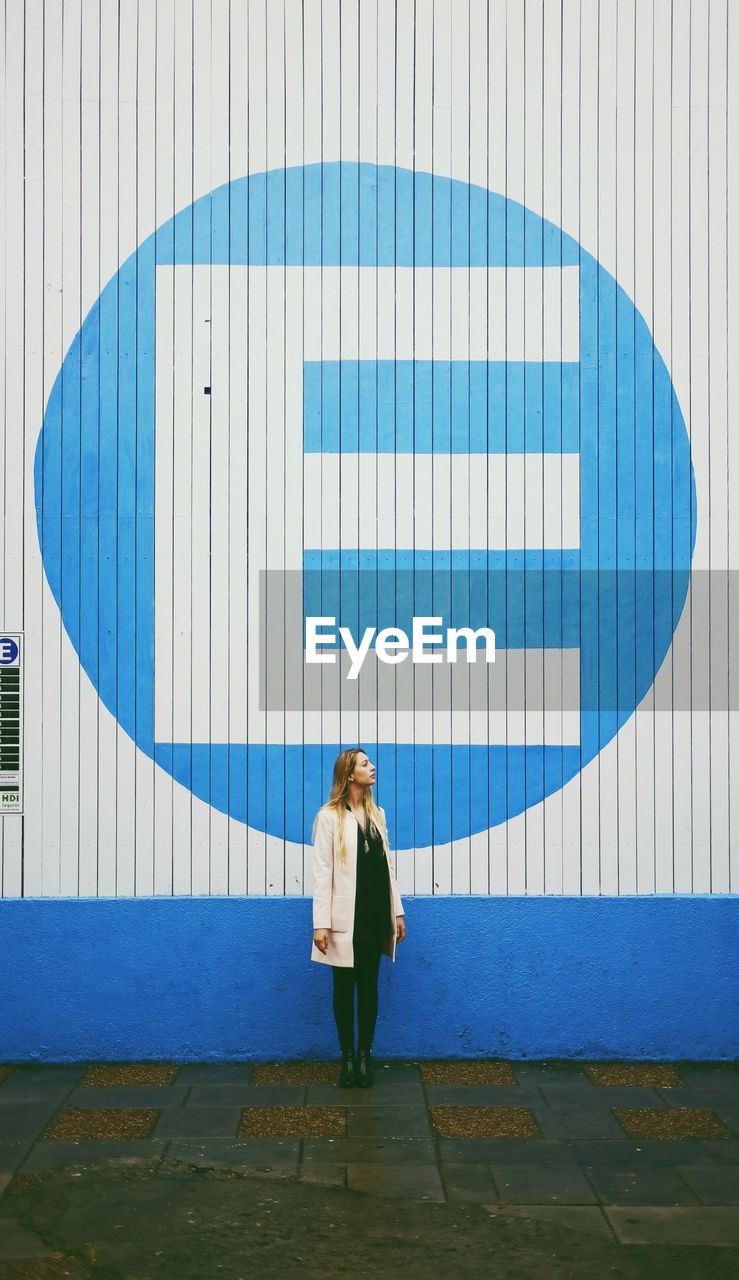Woman standing by letter e on wall
