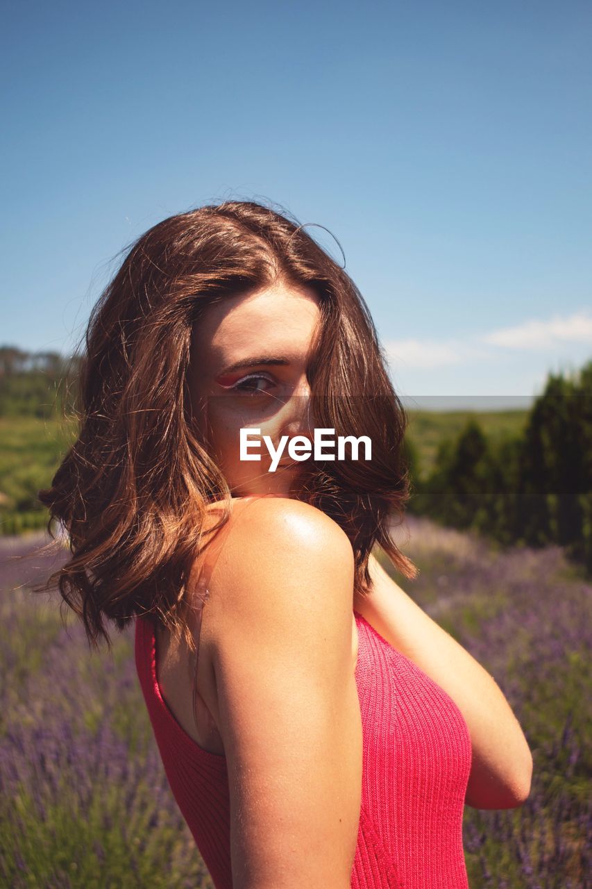 Portrait of beautiful woman on field against sky