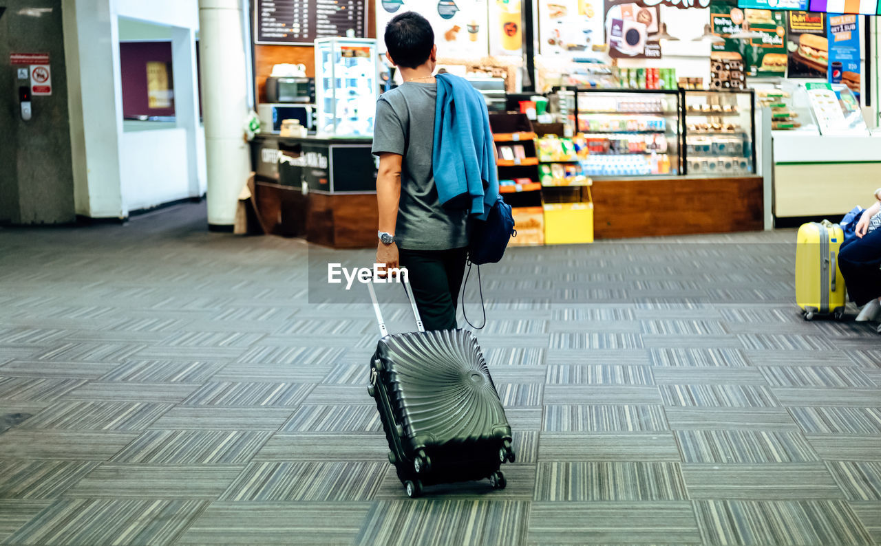 REAR VIEW OF MAN WALKING ON FLOOR IN CITY