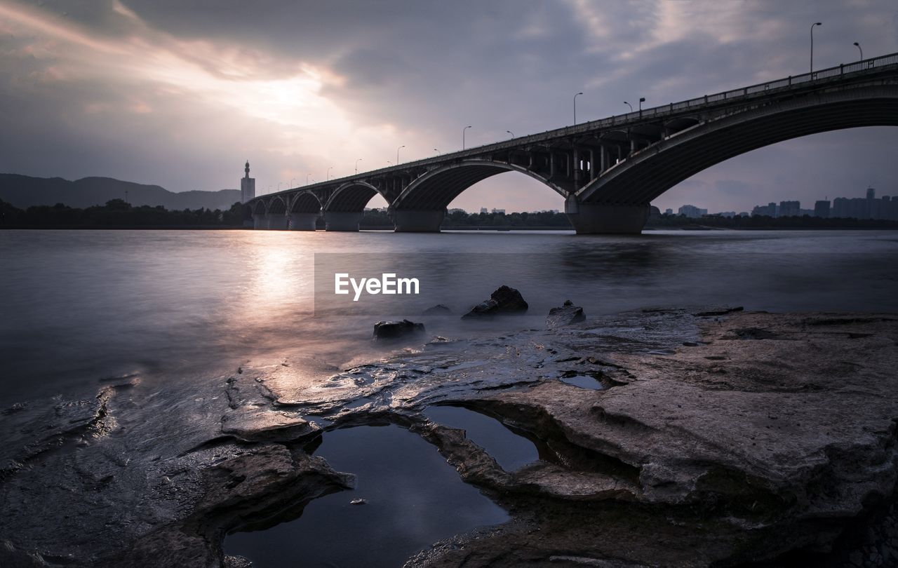 Bridge over river against sky during sunset