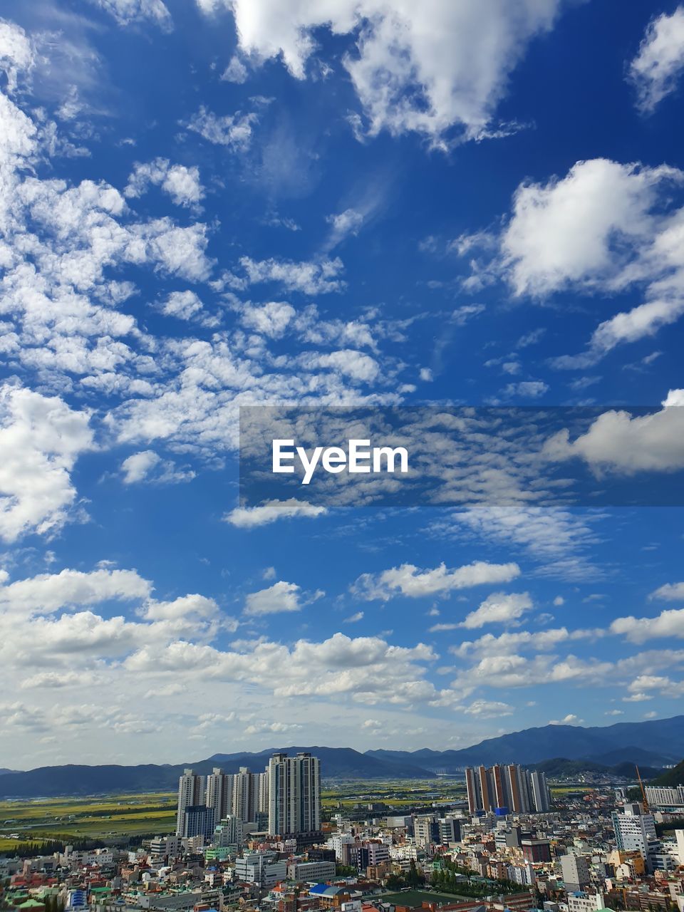 AERIAL VIEW OF BUILDINGS AGAINST CLOUDY SKY