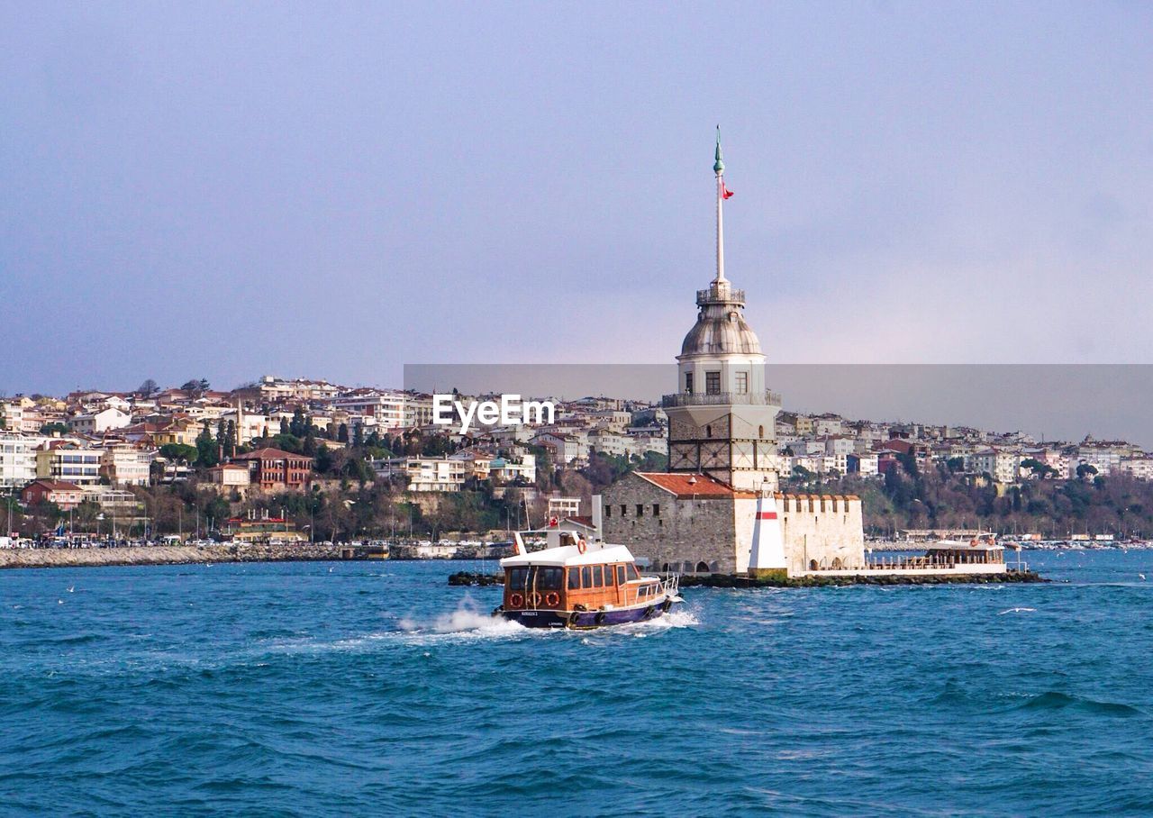 Boat in bosphorus strait by maiden tower against sky