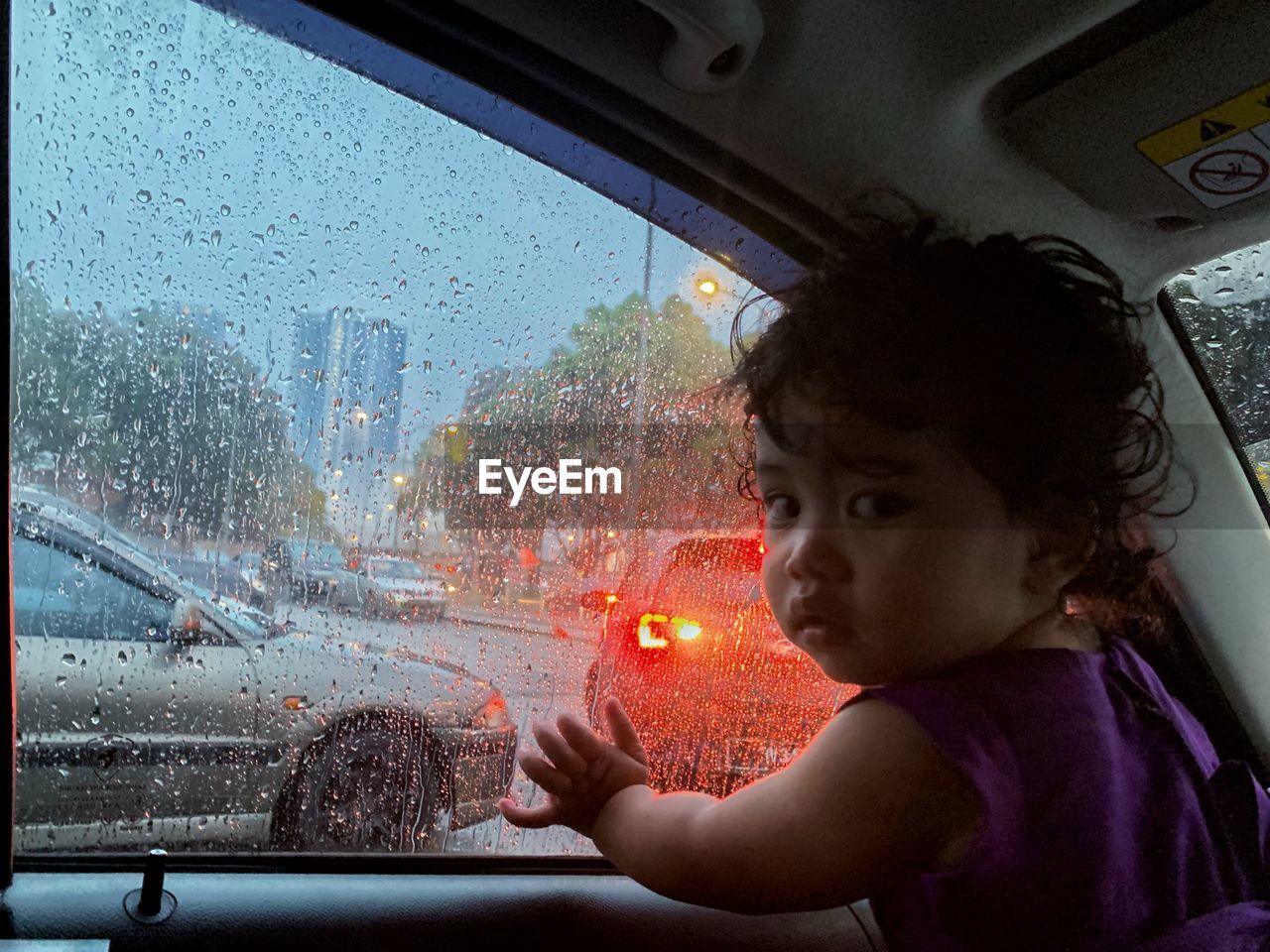 Girl looking through wet window during rainy season