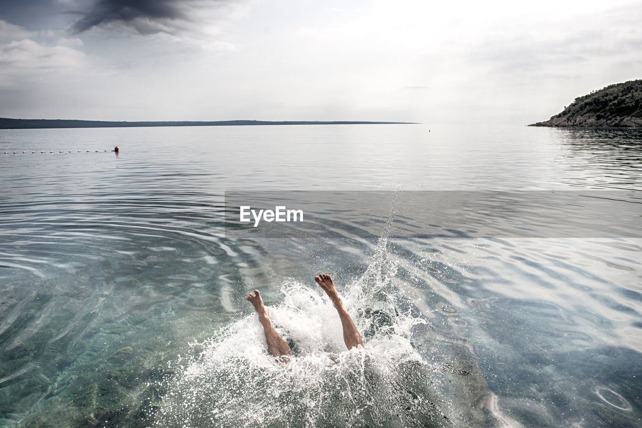 High angle view of woman drowning in sea against sky