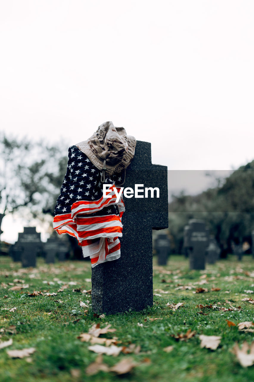 National american flag and army flag placed on gravestone in military cemetery on early autumn day