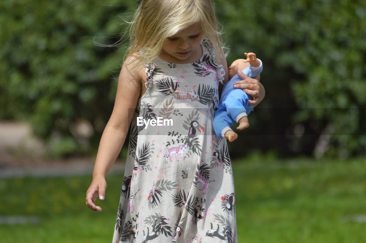 Girl carrying toy while walking on field