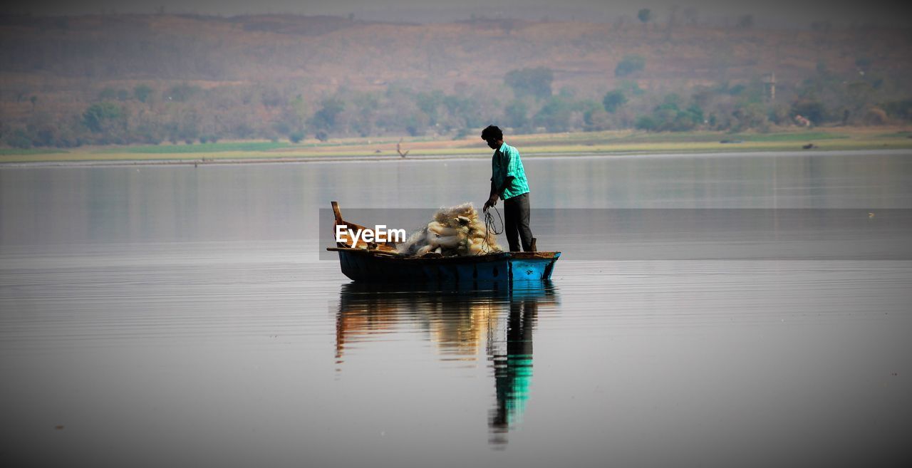 Fisherman standing in boat on river