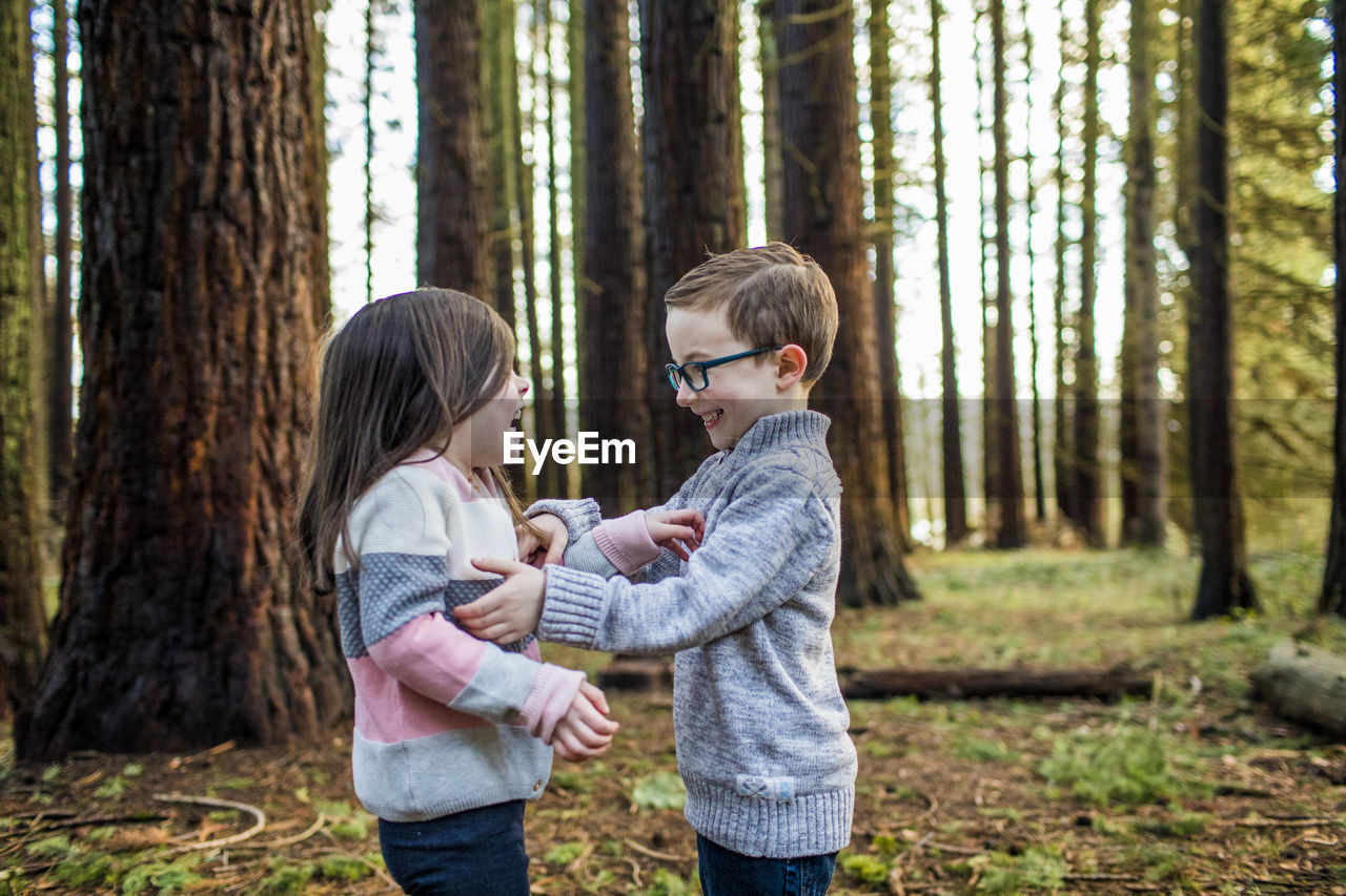 Playful boy and girl enjoying time outdoors in forest.