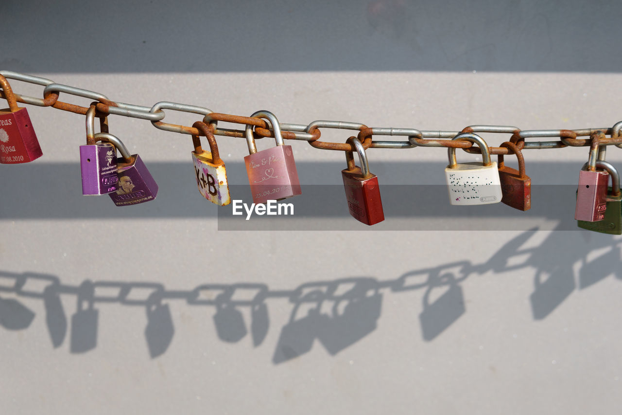 Close-up of multi colored padlocks hanging against wall