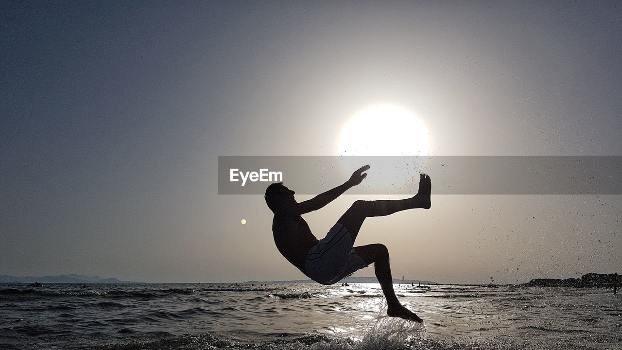 Silhouette person on beach against sky during sunset