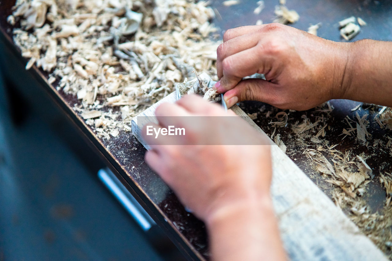 Midsection of person working on wooden plank.