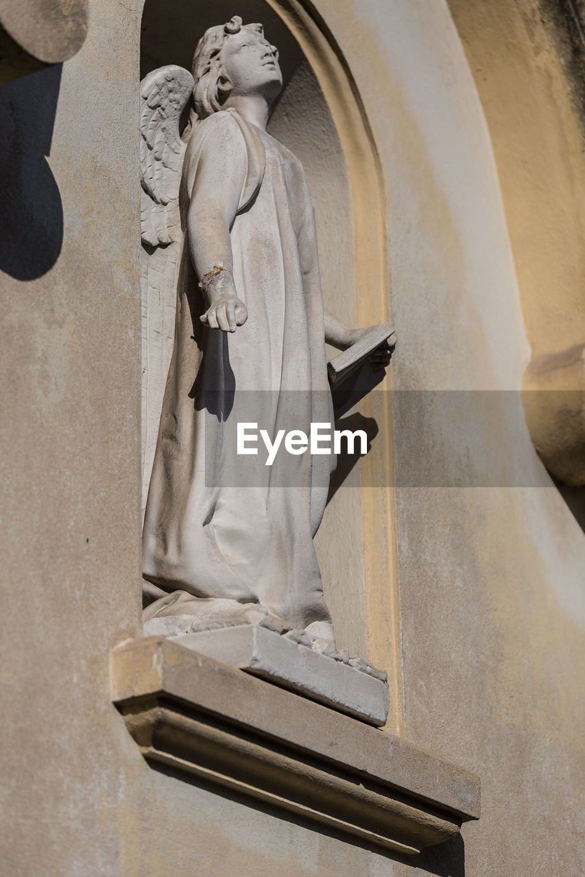 LOW ANGLE VIEW OF ANGEL STATUE AGAINST BUILDING AND TEMPLE