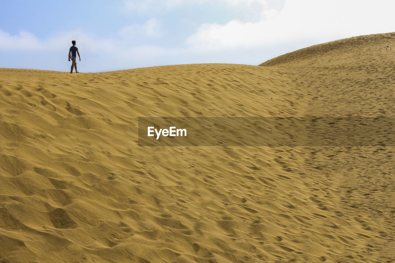 Teenage boy walking on sand at desert