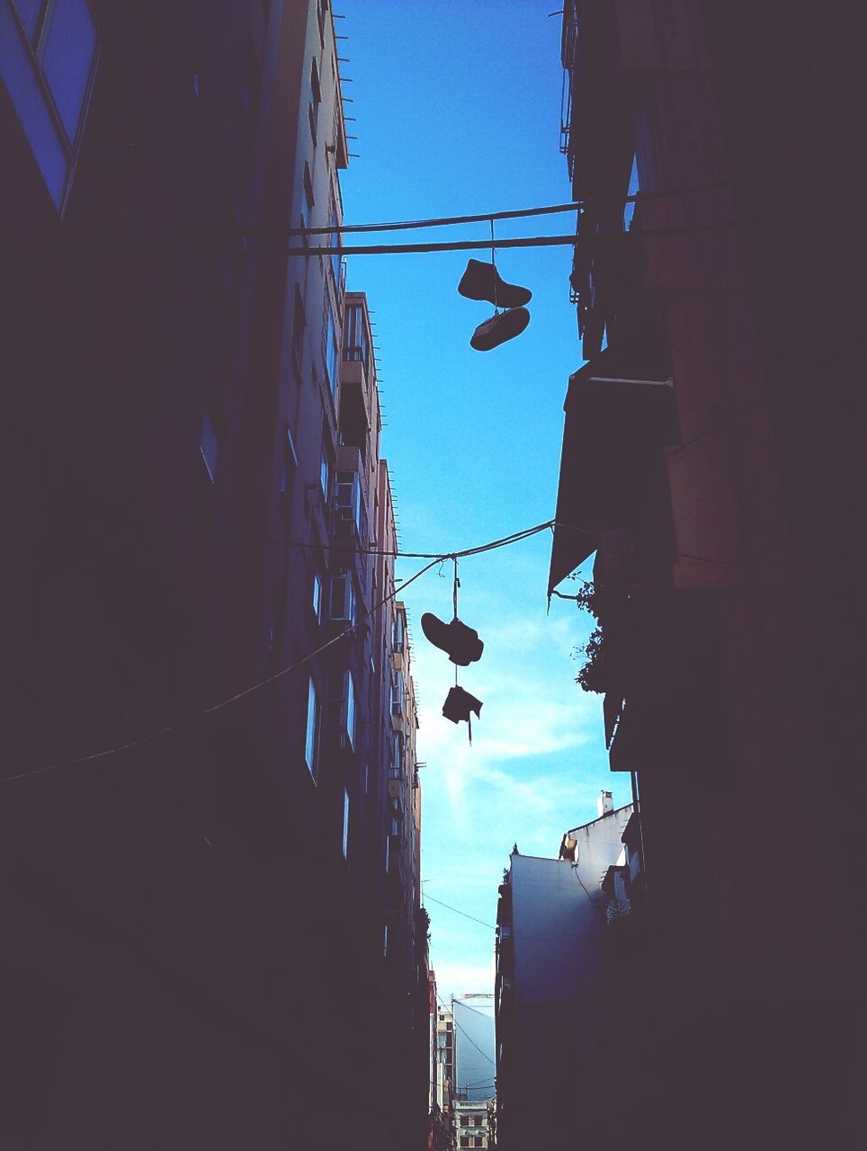 Low angle view of shoes hanging amidst buildings in city